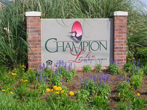 Champion Lake Apartments Big Sign Surrounded by Beautiful Flowers and Bushes